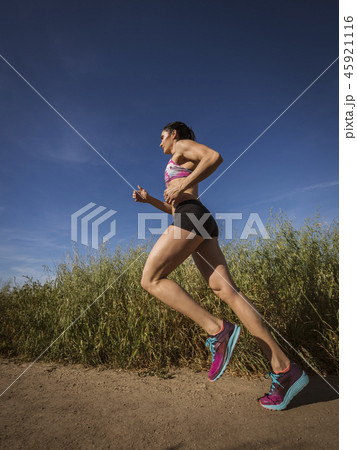 Mid adult woman jogging on path through field 45921116