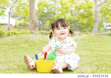 青空をバックに芝生の公園で1人遊ぶ幼い女の子。幸せ、育児、成長、健康、イメージ 45921416