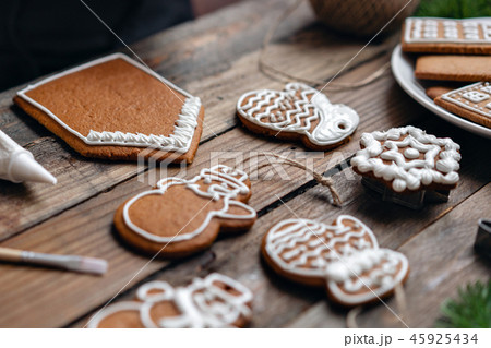 A lot of ginger biscuits in different form on brown wooden table. Decorated with white sweet glaze 45925434