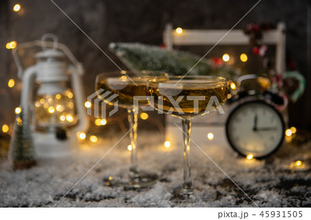 Photo of two champagne glasses on blurred background with Christmas tree, lantern, clock Photo of two champagne glasses on blurred background with Christmas tree, lantern, clock 45931505