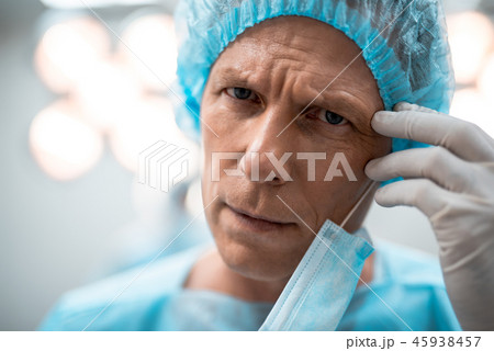 Close up of tired doctor frowning and touching his forehead Close up of tired doctor frowning and touching his forehead 45938457
