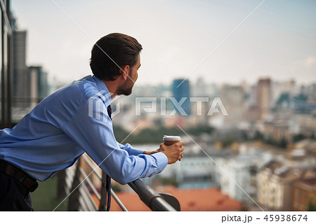 One male worker drinking coffee on office balcony One male worker drinking coffee on office balcony 45938674