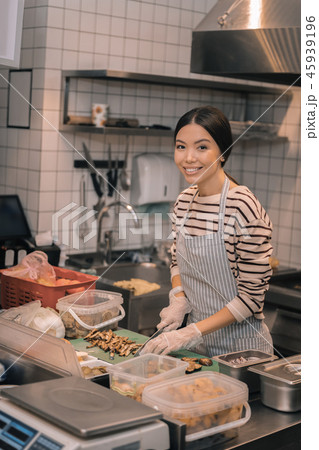 Dark-haired worker of restaurant wearing gloves while cutting in kitchen Dark-haired worker of restaurant wearing gloves while cutting in kitchen 45939196