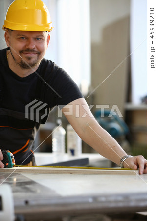 Arms of worker measuring wooden bar closeup Arms of worker measuring wooden bar closeup 45939210