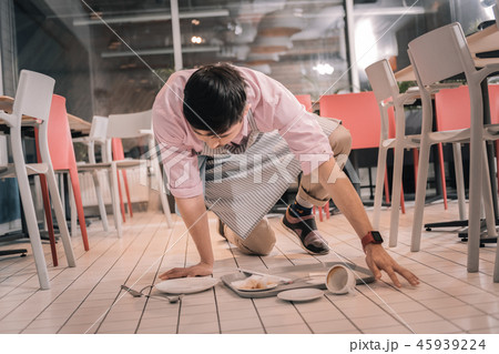 Dark-haired waiter cleaning the floor after dropping tray with food 45939224