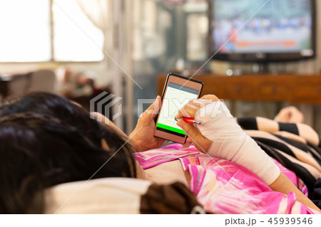 Senior patient hand injured with bandage lying down and using cell phone. Senior patient hand injured with bandage lying down and using cell phone. 45939546