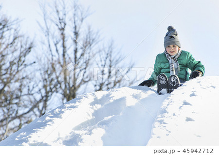 The boy in hat, scarf and green jacket slides down The boy in hat, scarf and green jacket slides down 45942712