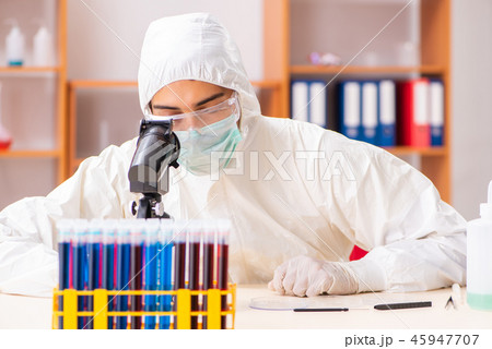 Young biochemist wearing protective suit working in the lab Young biochemist wearing protective suit working in the lab 45947707