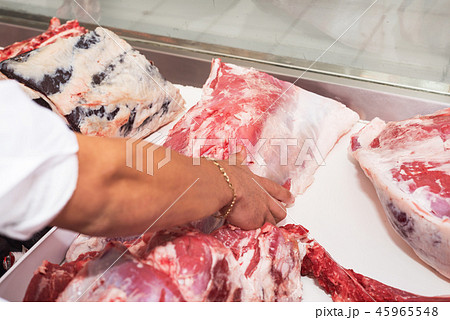 Butcher offering fresh meat at display in butchery Butcher offering fresh meat at display in butchery 45965548