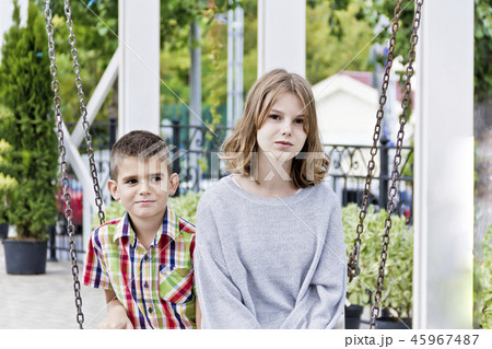 Brother and sister are riding on a swing 45967487