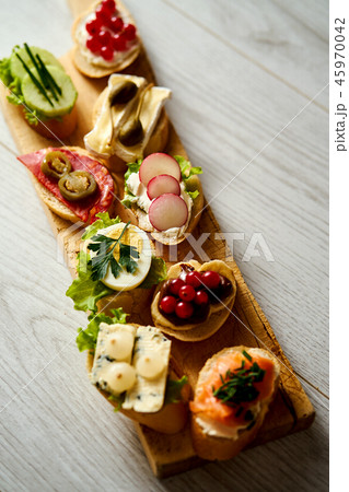 wooden board with colorful healthy mini sandwiches or tapas on a wooden table 45970042