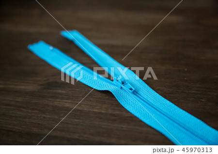 Blue clothing zipper on dark wood background Blue clothing zipper on dark wood background 45970313