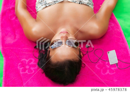 Woman on beach gets sun tan and listen music pink Woman on beach gets sun tan and listen music pink 45978378