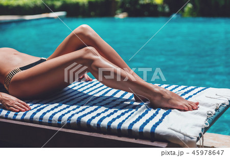 woman's legs in bikini relax near swimming pool woman's legs in bikini relax near swimming pool 45978647