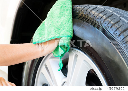 Women are wiping the car wheel with green textile 45979892