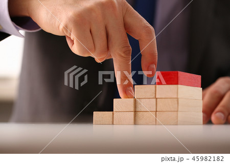 Male hand holds red wood block of stair Male hand holds red wood block of stair 45982182