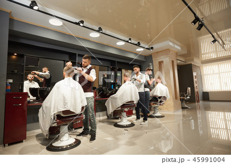 Male hairdressers servicing clients in barber shop 45991004