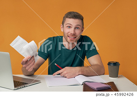 man sitting at his Desk with laptop and a notebook man sitting at his Desk with laptop and a notebook 45992426
