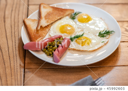 Breakfast food. American style breakfast with fried eggs, sausage, green peas and toast. The concept 45992603