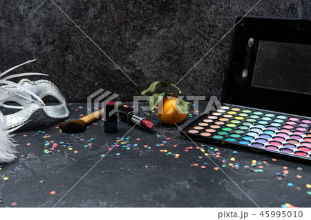 Image of christmas decoration, mandarin, brushes, lipstick, palette with shadows on black table 45995010