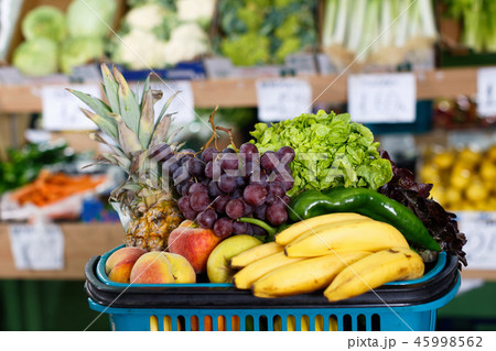 Shopping basket filled with fresh fruits and vegetables on background with showcase 45998562