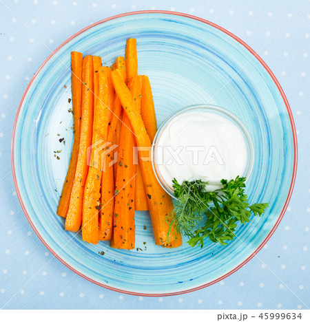 Tasty fried carrot sticks and served with sour cream at plate 45999634
