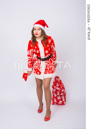 Holidays, Christmas and gifts concept - Beautiful woman in Santa costume with big and heavy bag of Holidays, Christmas and gifts concept - Beautiful woman in Santa costume with big and heavy bag of 46004060