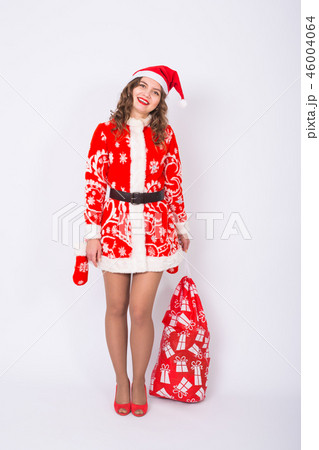 Holidays, Christmas and gifts concept - Beautiful woman in Santa costume with big and heavy bag of Holidays, Christmas and gifts concept - Beautiful woman in Santa costume with big and heavy bag of 46004064