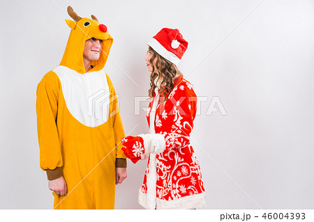 Fun, Christmas and holidays concept - happy woman in santa clothes with man in costume of deer are 46004393