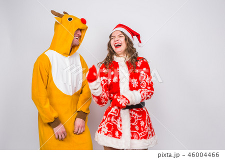 Holiday, Christmas and fun concept - Funny couple in deer costume and Santa Claus clothes are Holiday, Christmas and fun concept - Funny couple in deer costume and Santa Claus clothes are 46004466