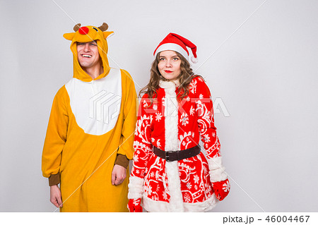 Fun, Christmas and holidays concept - happy woman in santa clothes with man in costume of deer are Fun, Christmas and holidays concept - happy woman in santa clothes with man in costume of deer are 46004467