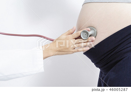 妊婦の大きなお腹を聴診器で診察する女医の手元のアップ 妊娠 診察 臨月 検査 産婦人科 女医イメージの写真素材