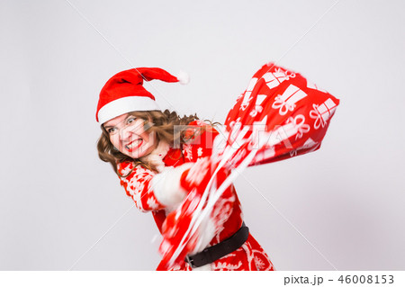 Holiday, Christmas and people concept - Angry woman in santa costume with bag of presents 46008153