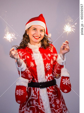 Christmas, holidays and people concept - woman in santa suit with lights and sparkles laughing. 46009097