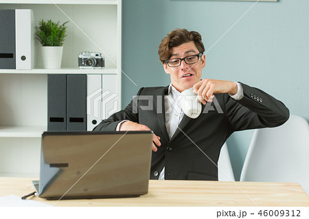 Business people, joke and fool's day concept - young funny businessman spilling tea in office 46009312