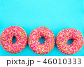 Three donuts with bright pink icing on blue  46010333