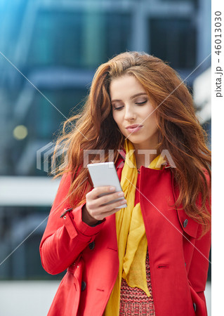 beautiful girl in red coat speaks by phone on the street 46013030
