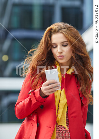 beautiful girl in red coat speaks by phone on the street 46013032