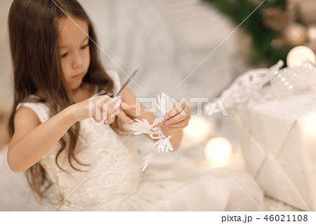 child girl makes paper snowflakes for decoration Christmas tree 46021108