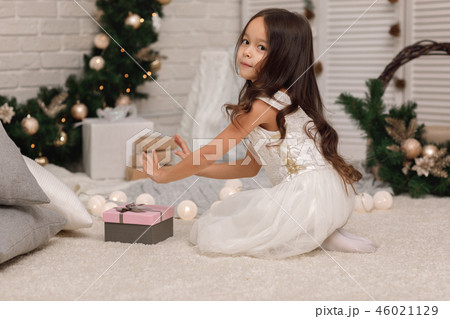 Pretty smiling girl holding Christmas gift in hand Pretty smiling girl holding Christmas gift in hand 46021129