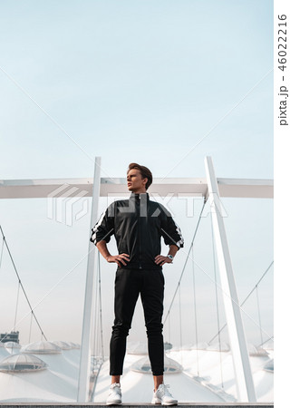 Young sportive man runner posing near stadium. He looks to the left 46022216