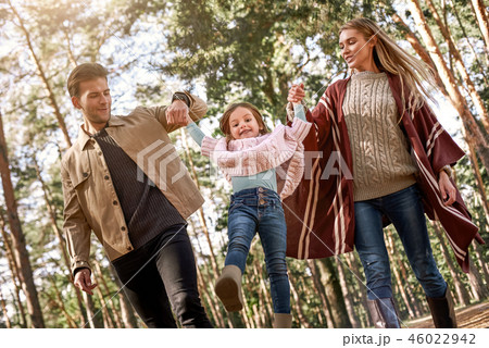 Young parents with little daughter in autumn forest. Bottom view Young parents with little daughter in autumn forest. Bottom view 46022942