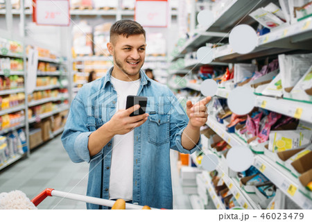 Man with cart makes purchase by the list on phone 46023479