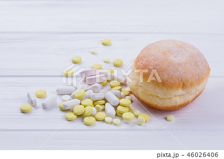 Donut and pills on wooden background. Donut and pills on wooden background. 46026406