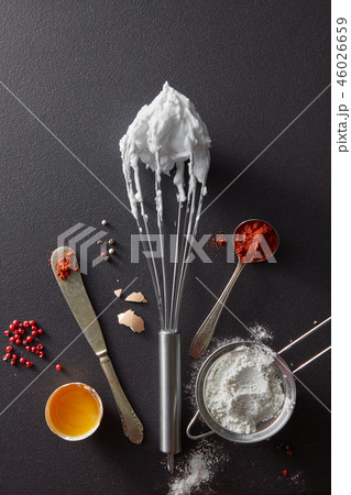 A set of knife with pepper, sieve with flour, metal whisk and boiled eggs on a black concrete 46026659