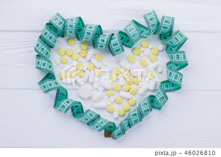 Heart-shaped measuring tape and pills. 46026810