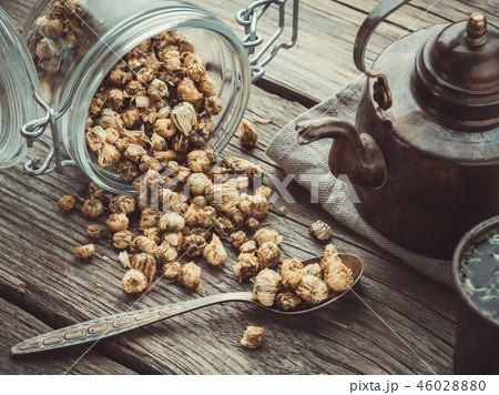 Old teapot, glass jar of chamomile buds and spoon. 46028880