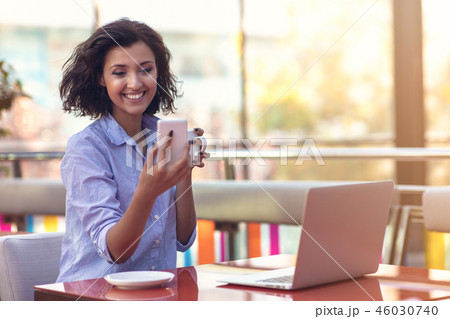 Businesswoman Using Phone While Working In Coffee Shop Businesswoman Using Phone While Working In Coffee Shop 46030740