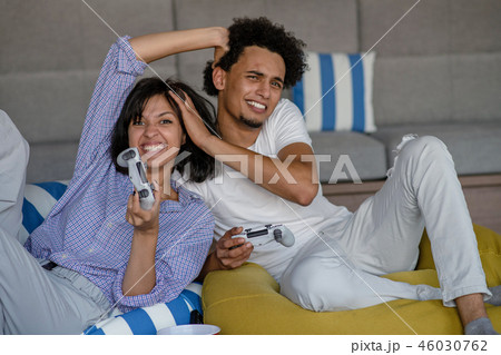 Playful young couple playing video games in their living room. 46030762