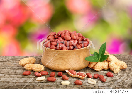 peanuts with leaf in bowl on old on wooden table with a blurry garden background 46034773
